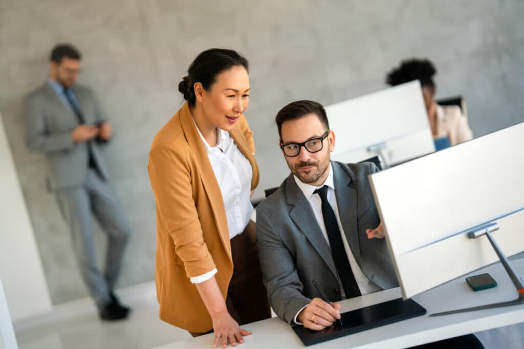 A man and woman working on a computer together in an office