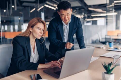 two coworkers on computer in office using malware protection tools to keep data safe